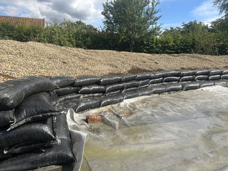 Sandbags forming a retaining wall beside gravel mound
